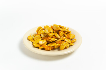 Pumpkin seeds in a saucer on a white background. Autumn harvest. Copy space. Horizontal orientation.