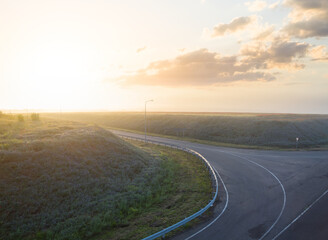asphalt road turn in a light of early morning sun, transportation scene