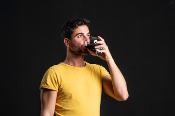 Man drinking red wine on black background