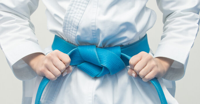hands grabbing blue karate belt