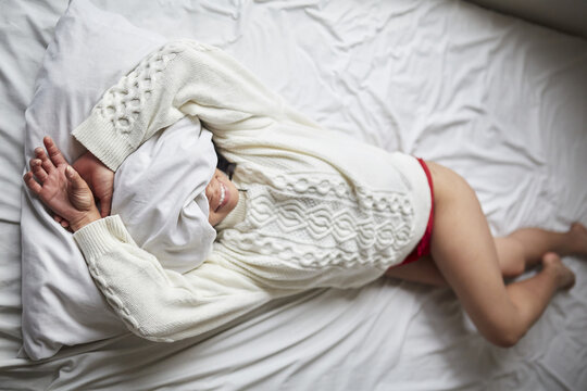 Young Latin woman laying on the bed happily smiling with her face covered