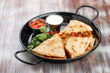Quesadilla with pork, cheese and paprika. In a metal frying pan. Traditional Mexican dish