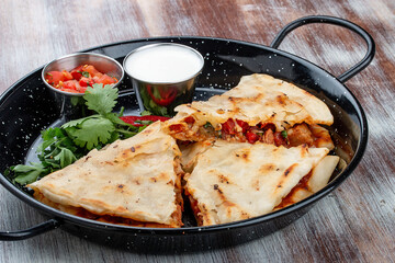 Quesadilla with pork, cheese and paprika. In a metal frying pan. Traditional Mexican dish