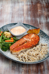 Salmon steak with cheese sauce, blanched vegetables and wild rice