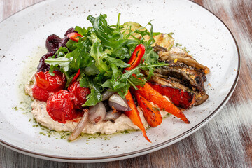 Grilled vegetables on a hummus cushion. Eggplant, pepper, tomato, zucchini, garlic.