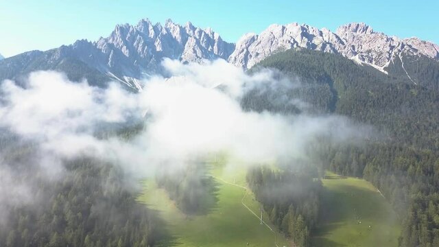 Drone above the clouds, Beautiful Mountain tops with green ski slope in summer, Innichen, Tyrol