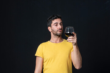 Man drinking red wine on black background