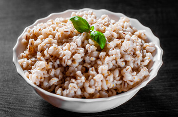 cooked pearl barley in bowl on a wooden table background