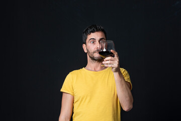 Man drinking red wine on black background