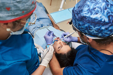 Professional dentists examine woman's teeth in the dental office.