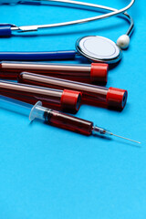 Top view of Medical equipment on blue background - stethoscope, syringe and test tube - healthcare and medicine concept