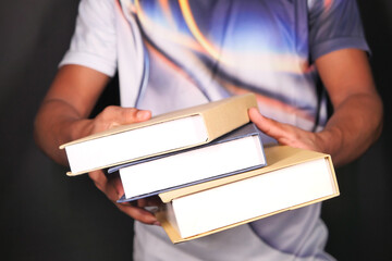 hand holding stack of books on color background 