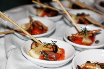 Medium close up shot of a table with appetizers of fresh tuna and mushrooms in small white plates