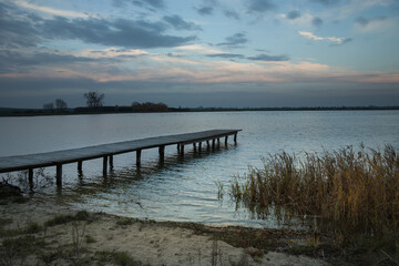 Fototapeta premium Wooden pier and reeds on the shore of the lake