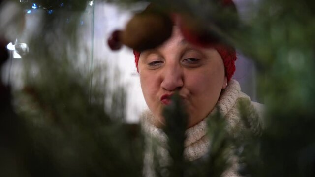 Woman Looking Inside Christmas Tree Blowing Kisses And Saying Hi To Camera