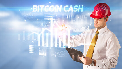 Handsome businessman with helmet drawing BITCOIN CASH inscription, architecture business plan concept