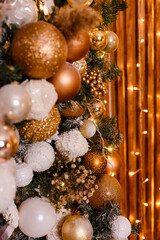 Fototapeta na wymiar beautiful New Year's decor. Christmas tree branches decorated with gold and white balls. elements of Christmas decor. lights of the garland.