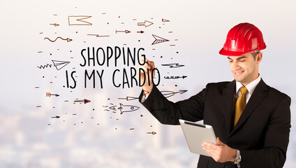 Handsome businessman with helmet drawing SHOPPING IS MY CARDIO inscription, contruction sale concept