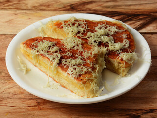 Cheese grilled Bun maska an Iranian popular dish that contains butter and sweet bun topped with cheese served in white plate, selective focus