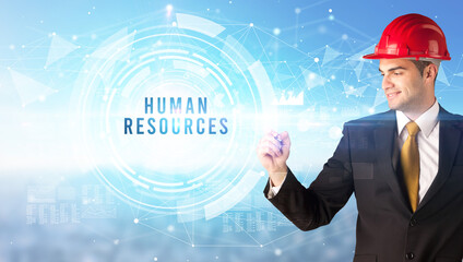 Handsome businessman with helmet drawing HUMAN RESOURCES inscription, contruction business concept