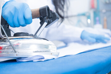 Woman holding a professional iron in a dry-cleaning business.Woman working concept.Copy space.Focus selective