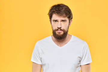 Bearded man emotions gestures with hands facial expression white t-shirt yellow background