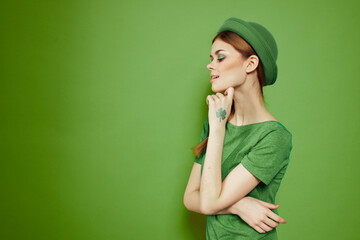 Nice girl with a shamrock on her hand on a green background holidays St. Patrick's Day fun hat on her head 