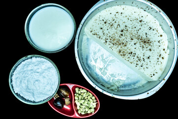 kharvas in cake pan with bowl of milk and bowl of sugar power