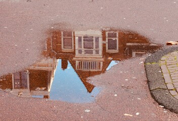 upside down reflection of an Amsterdam house on a puddle on the street