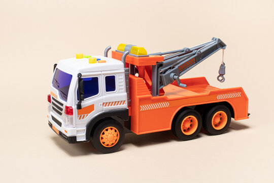 Toy orange tow truck on beige background. Children's car for loading and transporting cars.