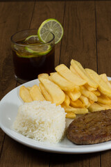 Tasty combination of hamburger with rice and fries. A refreshing glass of cola soda with lemons to accompany. Vertical photograph with space for texts.