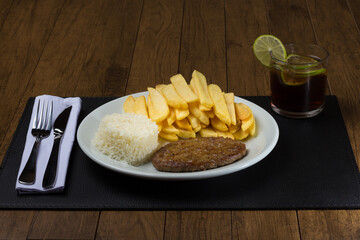 Dish combined with a tasty hamburger with rice and french fries, accompanied by a refreshing glass of cola soft drink with slices of lemons. Gastronomic photography. Popular food.