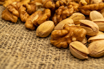 Pistachios and walnuts lie on the sacking. Close up.