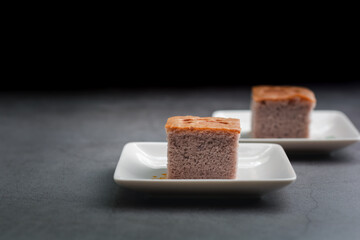 A square-cut of sweet potato cake on a white plate in the kitchen. Bakery and beverage concept.