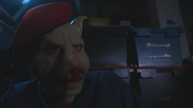 Man in pig mask suddenly wakes up and hyperventilates in a warehouse