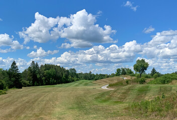 Fototapeta na wymiar A green golf course and blue cloudy sky on a beautiful summer day in Canada