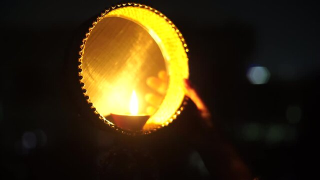 diya oil lamp placed on a chalni sieve which has been ornately decorated and is held up against the sky to look at the moon on the hindu festival of karvachauth after which women break their fast held
