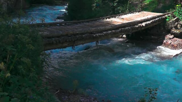 Log trestle bridge (without support, construction of thick long trunks) across mountain rapid river (dalles) for driving cattle (stock driving road on mountain pastures). Super slow motion 1000 fps
