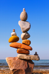 Fototapeta na wymiar Rock zen Pyramid of balanced stones against the background of the sea and blue sky.