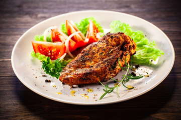 Fried chicken breast with boiled potatoes and fresh vegetables on wooden table
