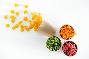 Multicolored pasta in a disposable kraft paper cups on a white background. Top view. Copy, empty space for text