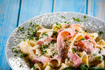 Pasta carbonara on white plate on wooden table
