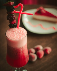 Milkshake on wooden table close up in coffee shop , strawberries and cheesecake around it