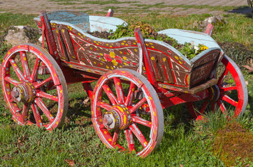 Karpenissi, Greece. A colorful old cart on the grass. Painted with brown, red, yellow, green, light blue colors. It contains soil and leaves. It is a sunny spring morning 
