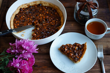 slice of homemade nut tart on a white plate on a dark wooden background