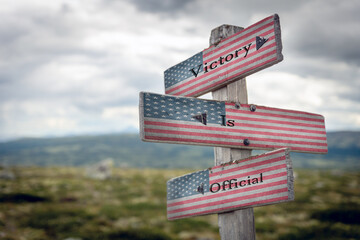 victory is official text on wooden signpost outdoors with the american flag to simulate the 2020...