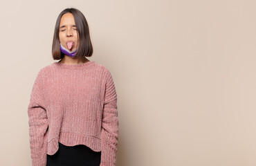 young woman with cheerful, carefree, rebellious attitude, joking and sticking tongue out, having fun