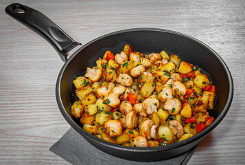 Fried potato with mushrooms in a frying pan