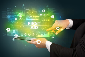 Close-up of a touchscreen with FIRST AID inscription, medical concept