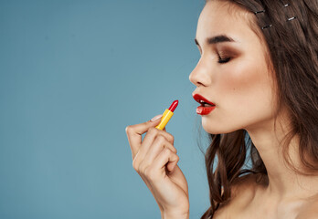 Red lipstick on blue background and brunette model female hands cropped view